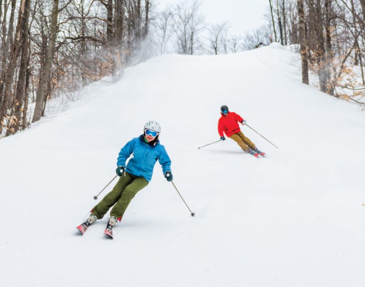 Man and Woman Skiing Down Hill