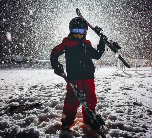 Young Boy Posing with Skis at Night