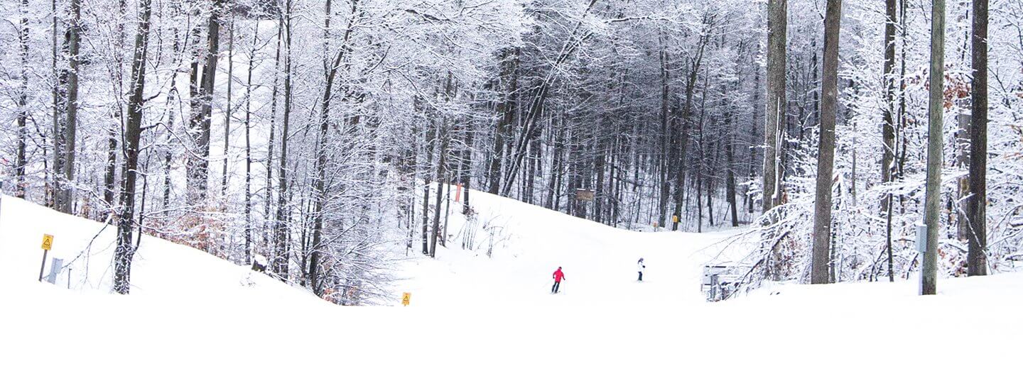 Looking down Schuss Mountain and two skiers in the background