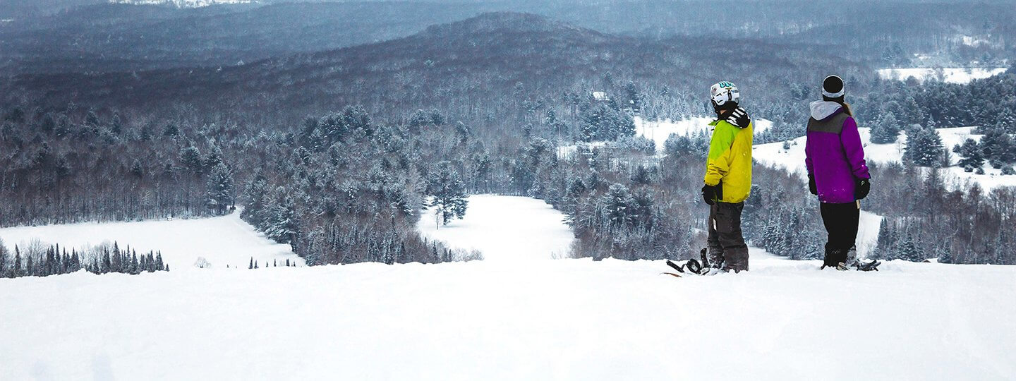 Two snowboarders looking at Schuss Mountain's vista