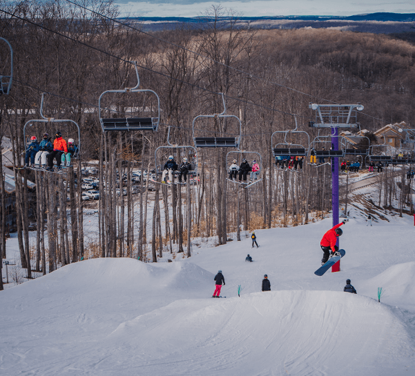 Looking down purple daze at chairlift, terrain park and skiers/boarders