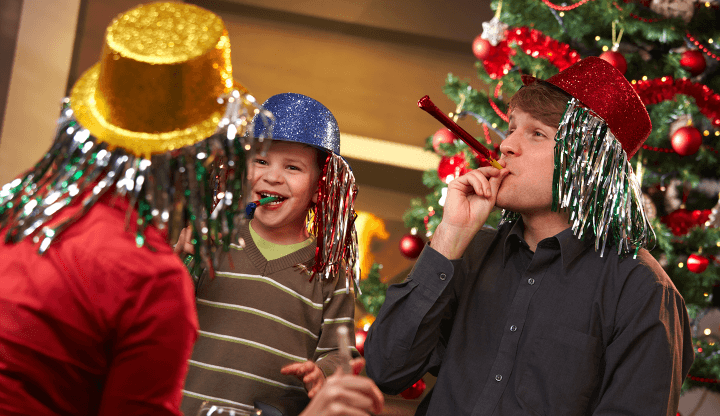 family blowing noisemakers - celebrating new year's eve