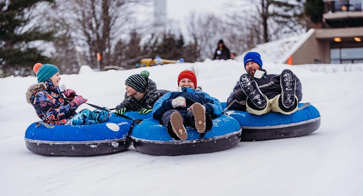 Dad and Three Children are all smiles as they are tubing at Summit Mountain