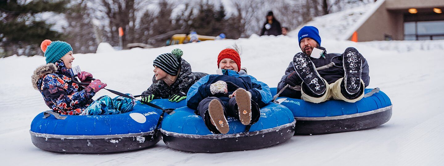 Dad and Three Children are all smiles as they are tubing at Summit Mountain