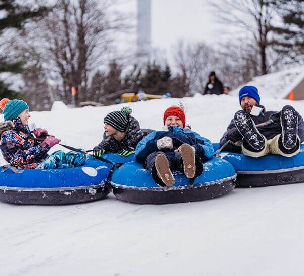 Dad and Three Children are all smiles as they are tubing at Summit Mountain