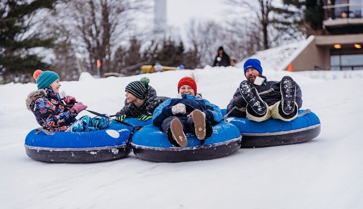 Dad and Three Children are all smiles as they are tubing at Summit Mountain