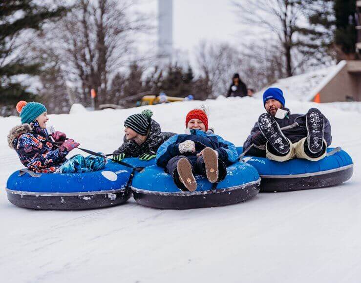 Dad and Three Children are all smiles as they are tubing at Summit Mountain