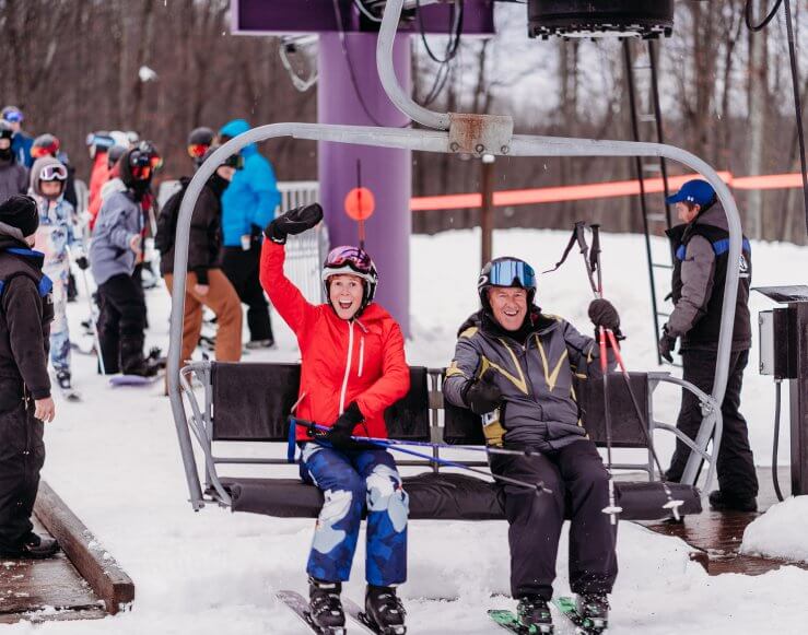 Two skiers just getting on the chairlift
