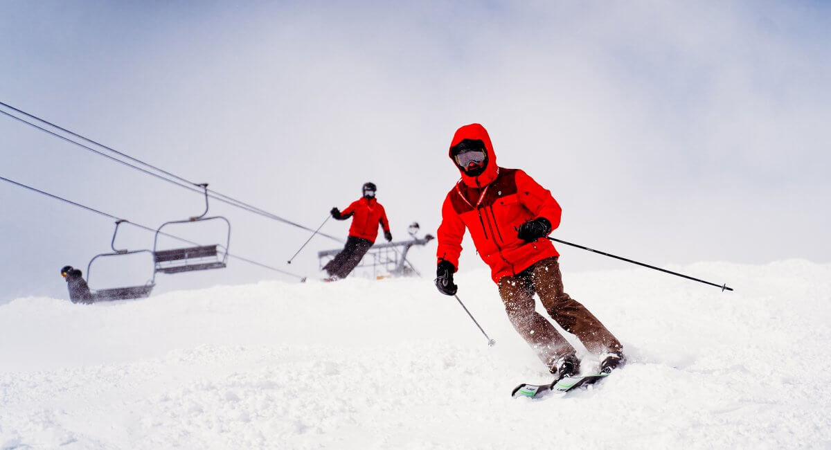 Two skiers in orange