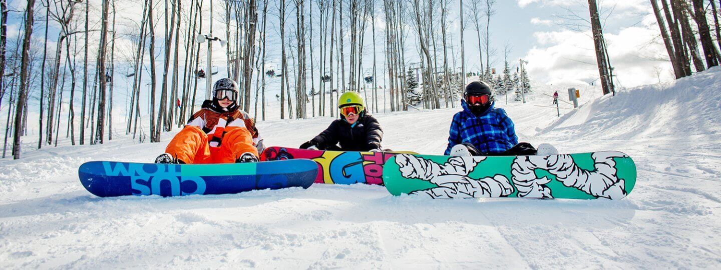 Three snowboarders sitting down