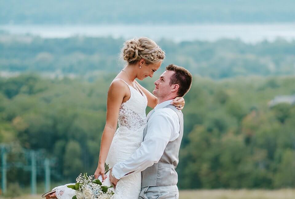 Groom picking up his bride with Lake Bellaire in the background