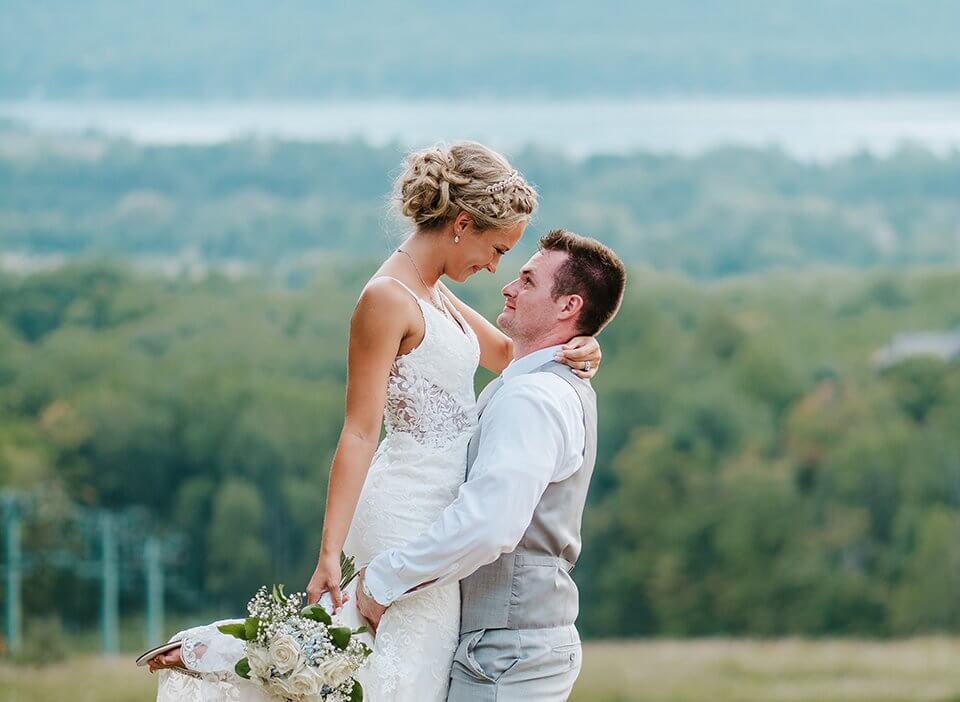 Groom picking up his bride with Lake Bellaire in the background