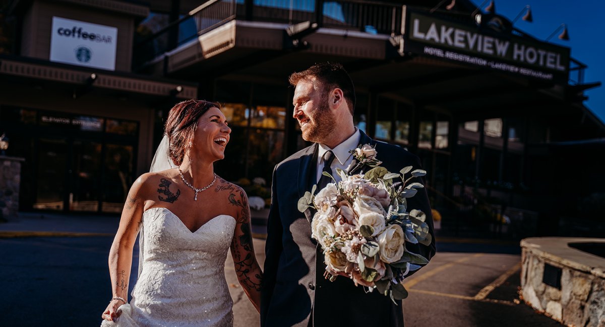 Bride and Groom walking with The Lakeview Hotel in the background