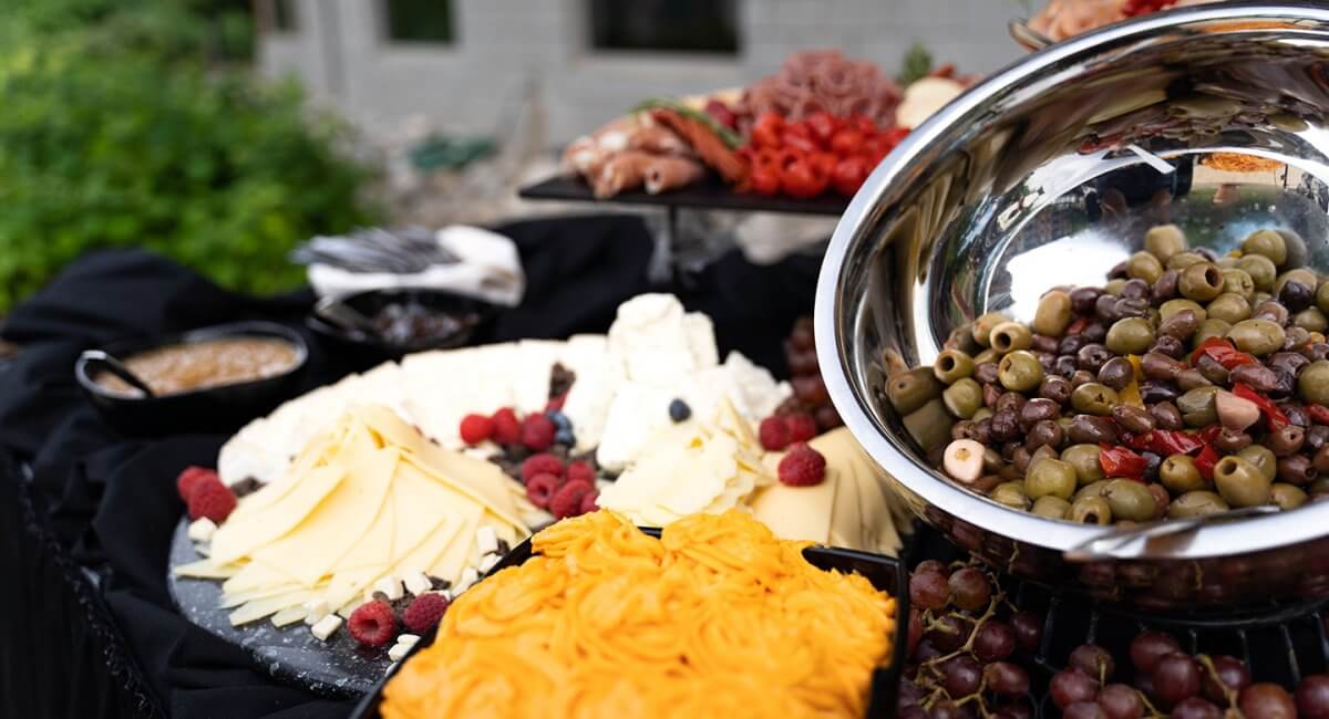 Charcuterie board display including green olives, grapes, cheeses and meats