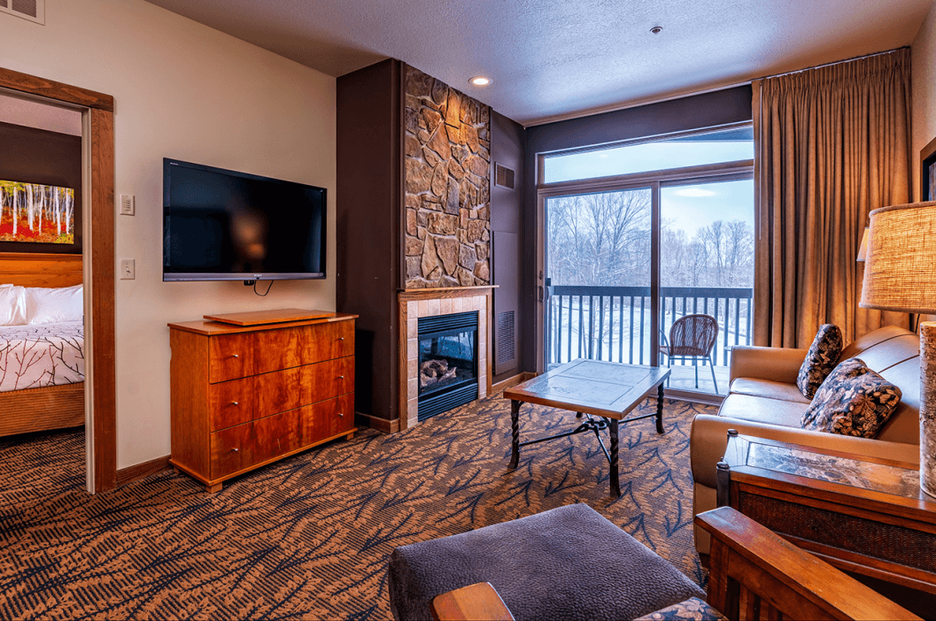 Cedar River 1 Bedroom Suite Living Room Area overlooking fireplace, deck, and television. Entryway to the bedroom in the background.