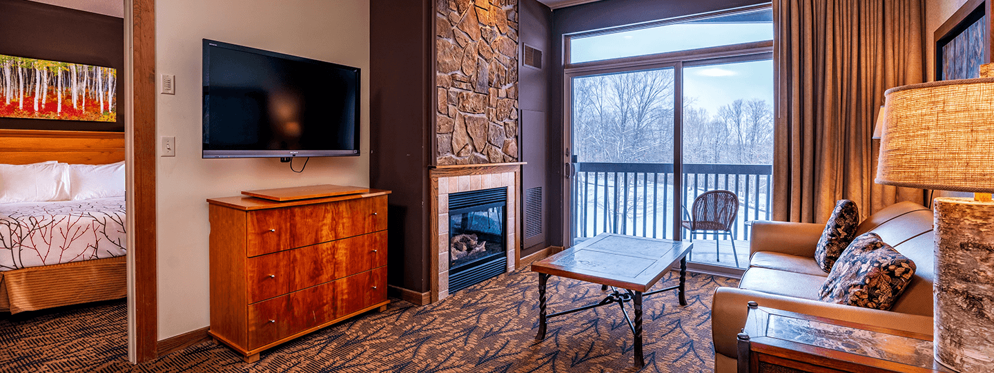 Cedar River 1 Bedroom Suite Living Room Area overlooking fireplace, deck, and television. Entryway to the bedroom in the background.