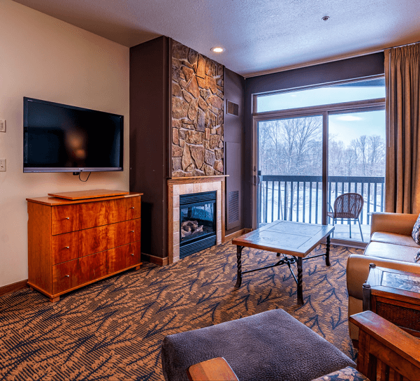 Cedar River 1 Bedroom Suite Living Room Area overlooking fireplace, deck, and television. Entryway to the bedroom in the background.