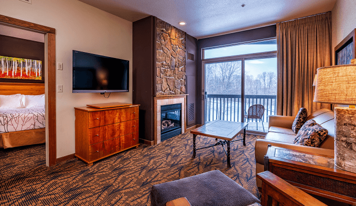 Cedar River 1 Bedroom Suite Living Room Area overlooking fireplace, deck, and television. Entryway to the bedroom in the background.