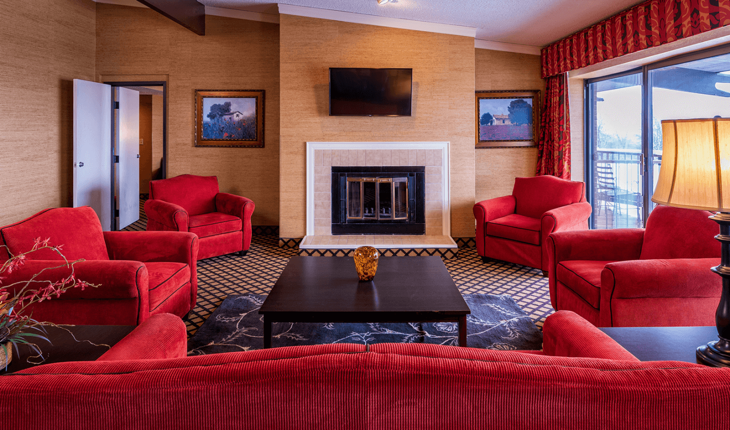 Living room area of presidential suite, overlooking couch and chairs, fierplace and flat screren tv on the wall