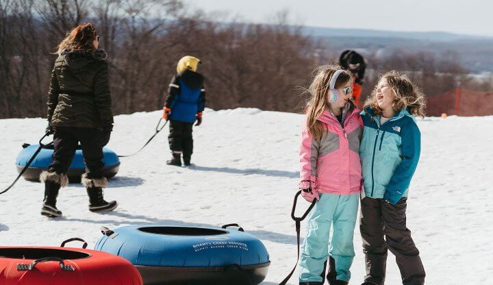 Two little girls holding tubes at the bottom of the tubing park