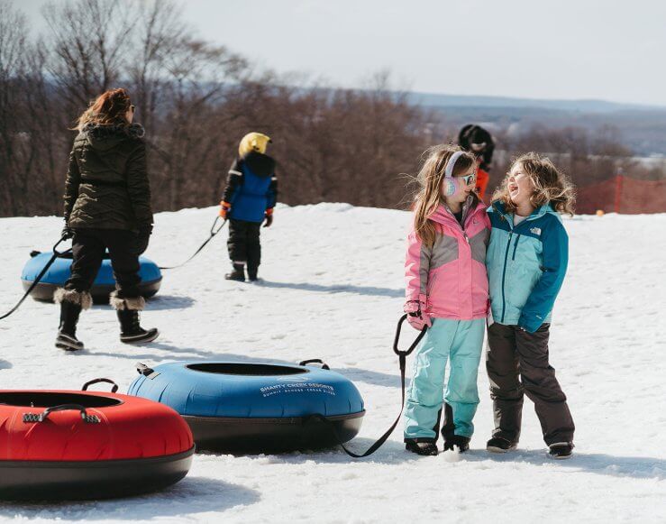 Two little girls holding tubes at the bottom of the tubing park