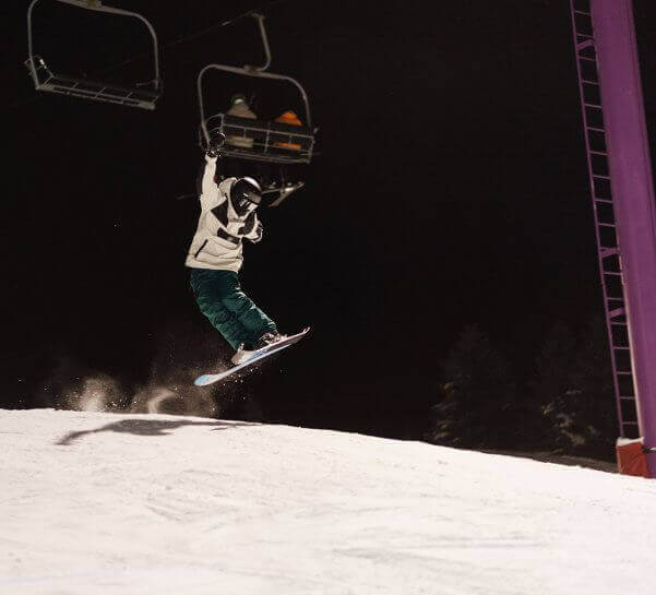 Skier hitting a jump on Purple Daze Terrain Park at Night