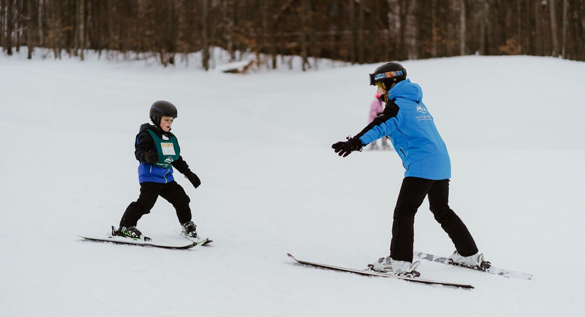 Ski Instructor teaching little boy how to ski