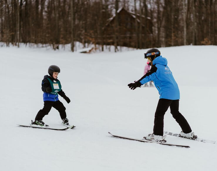 Ski Instructor teaching little boy how to ski