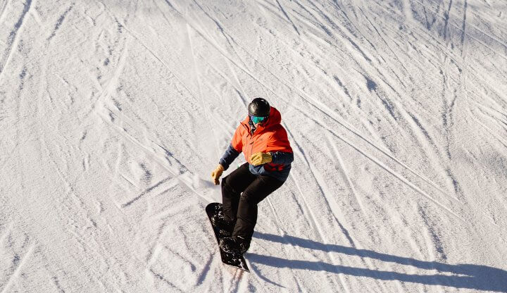 View of Snowboarder from Overhead in Orange Jacket and Black Board