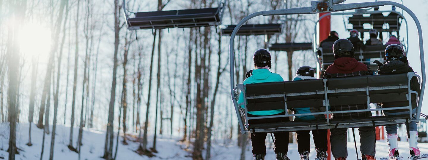 Family of Four Skiiers Riding Up the Red Chairlift