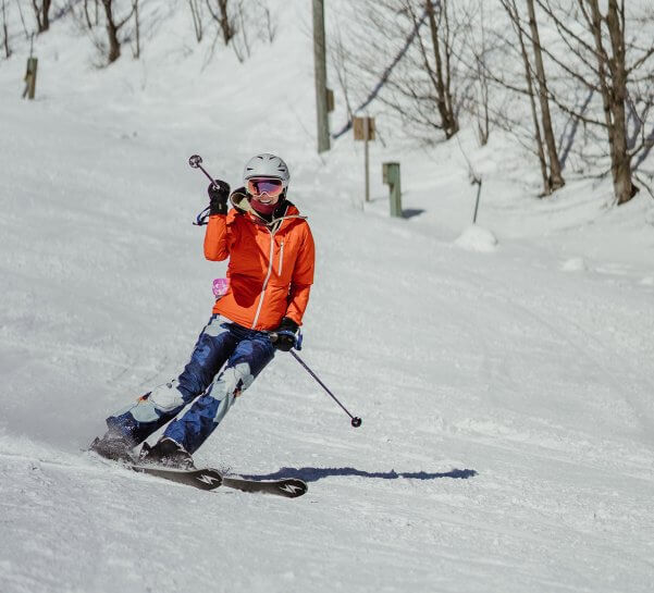 Skier in Orange Jacket and Blue Camo Pants Skiing Down the Hill