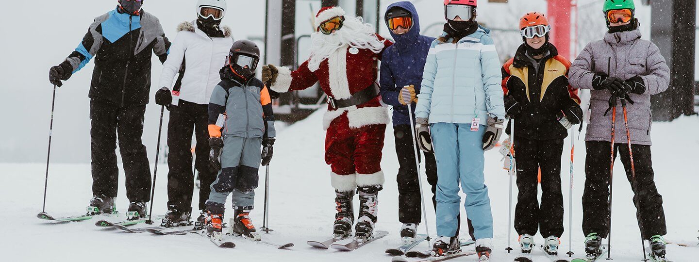 Santa posing with a family at the top of Schuss Mountain