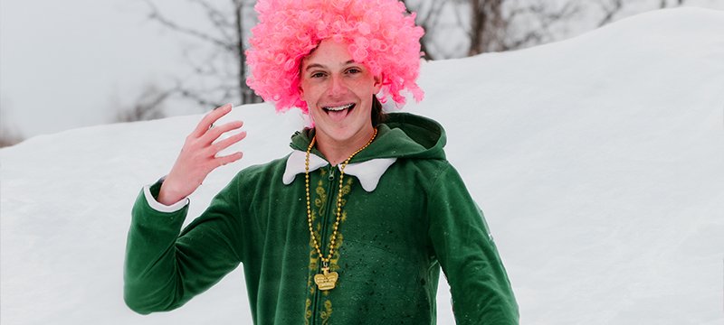 Boy dressed up as leprechan with a pink wig on the ski slopes