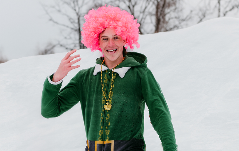 Boy dressed up as leprechan with a pink wig on the ski slopes