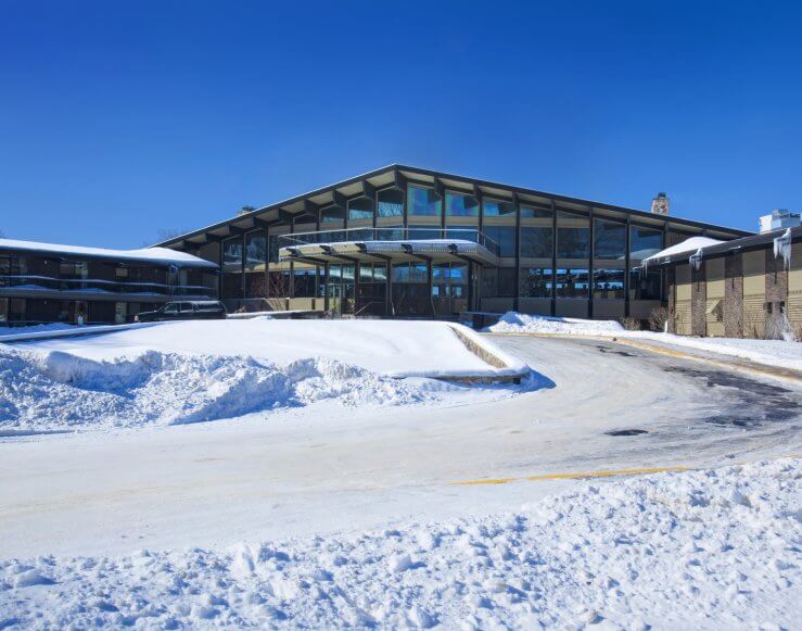 a lodge in the background with snow and a road in the foreground