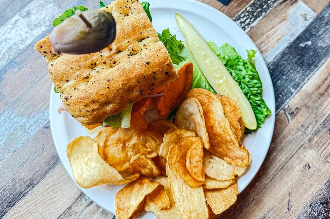 River Bistro's Dagwood Sandwich served with a pickle and dill pickle chips and Short's beer.