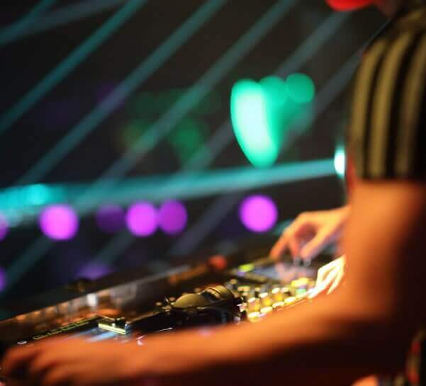 Hands of a DJ playing music on a soundboard