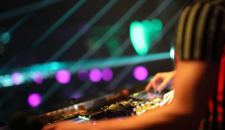 Hands of a DJ playing music on a soundboard