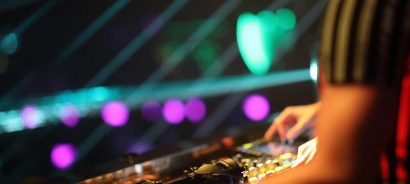 Hands of a DJ playing music on a soundboard