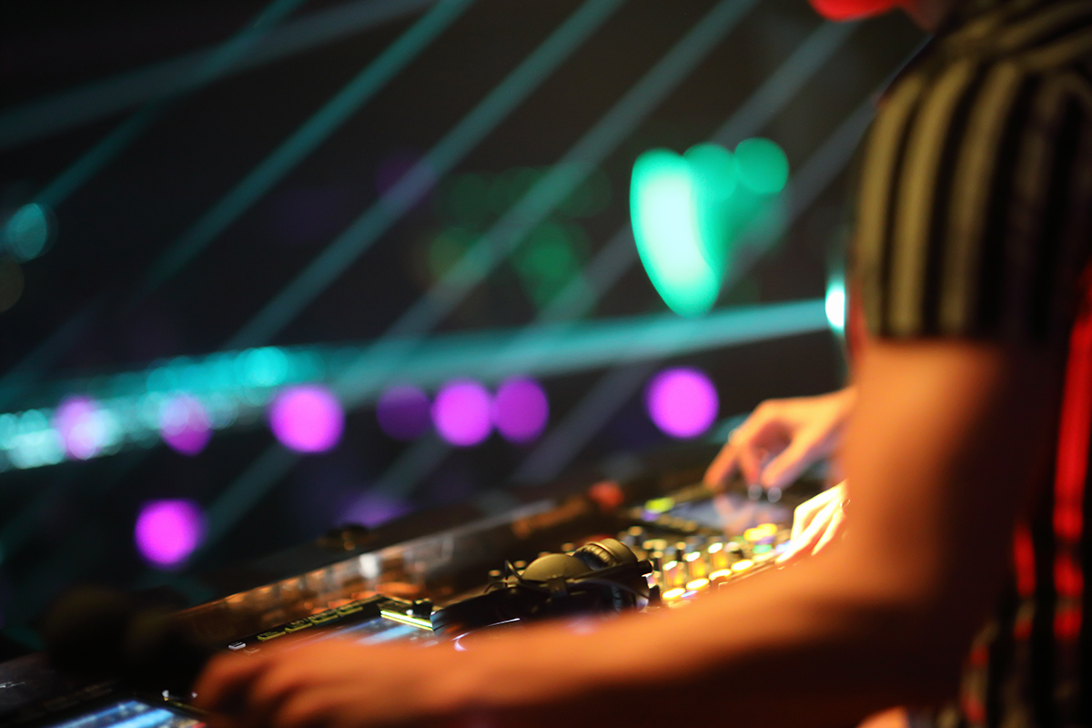 Hands of a DJ playing music on a soundboard